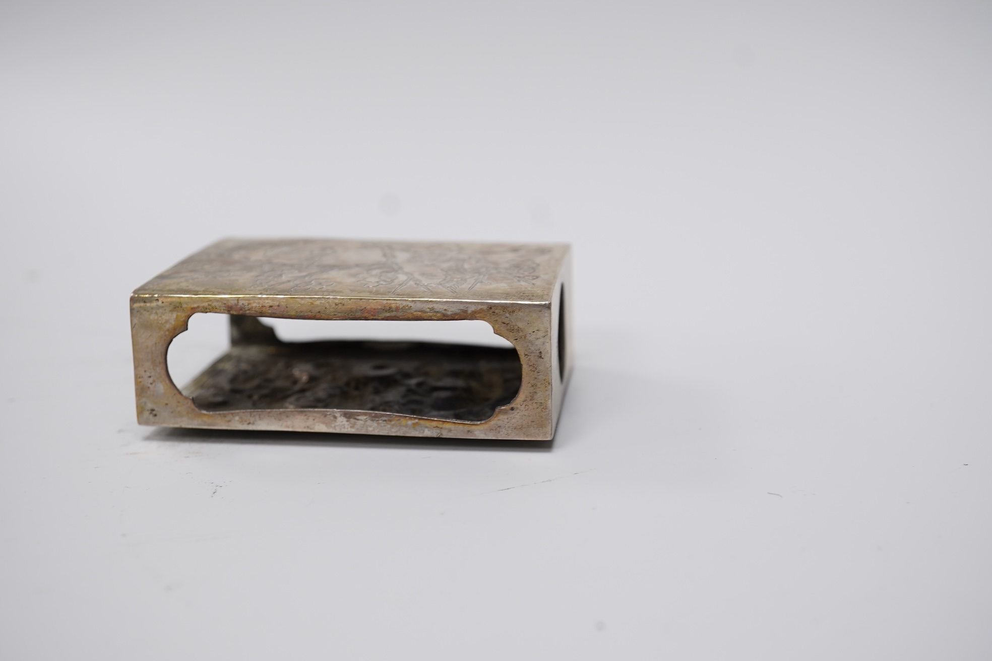 A Chinese Export white metal matchbox holder, with Chinese character mark stamp, embossed and engraved with dragon and prunus, 60mm and a pair of white metal figural menu holders, unmarked.